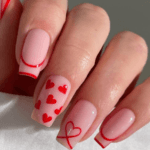 Red Valentine nail design with hearts and polka dots.