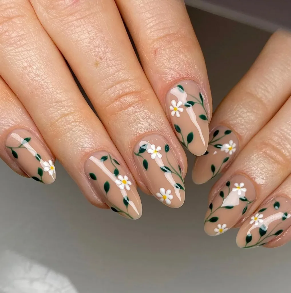 Soft nude nails with delicate white daisies and yellow centers.