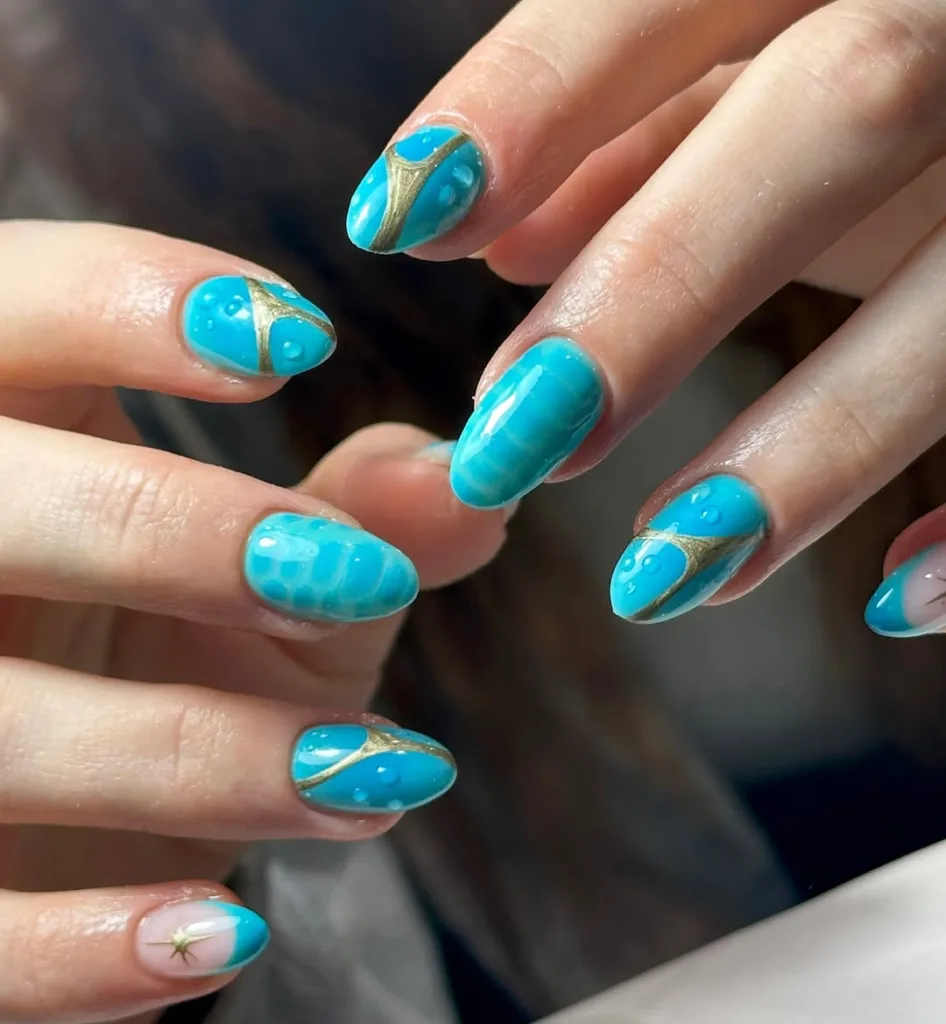  Abstract blue nails with water droplet textures and gold accents for beachy vibes.